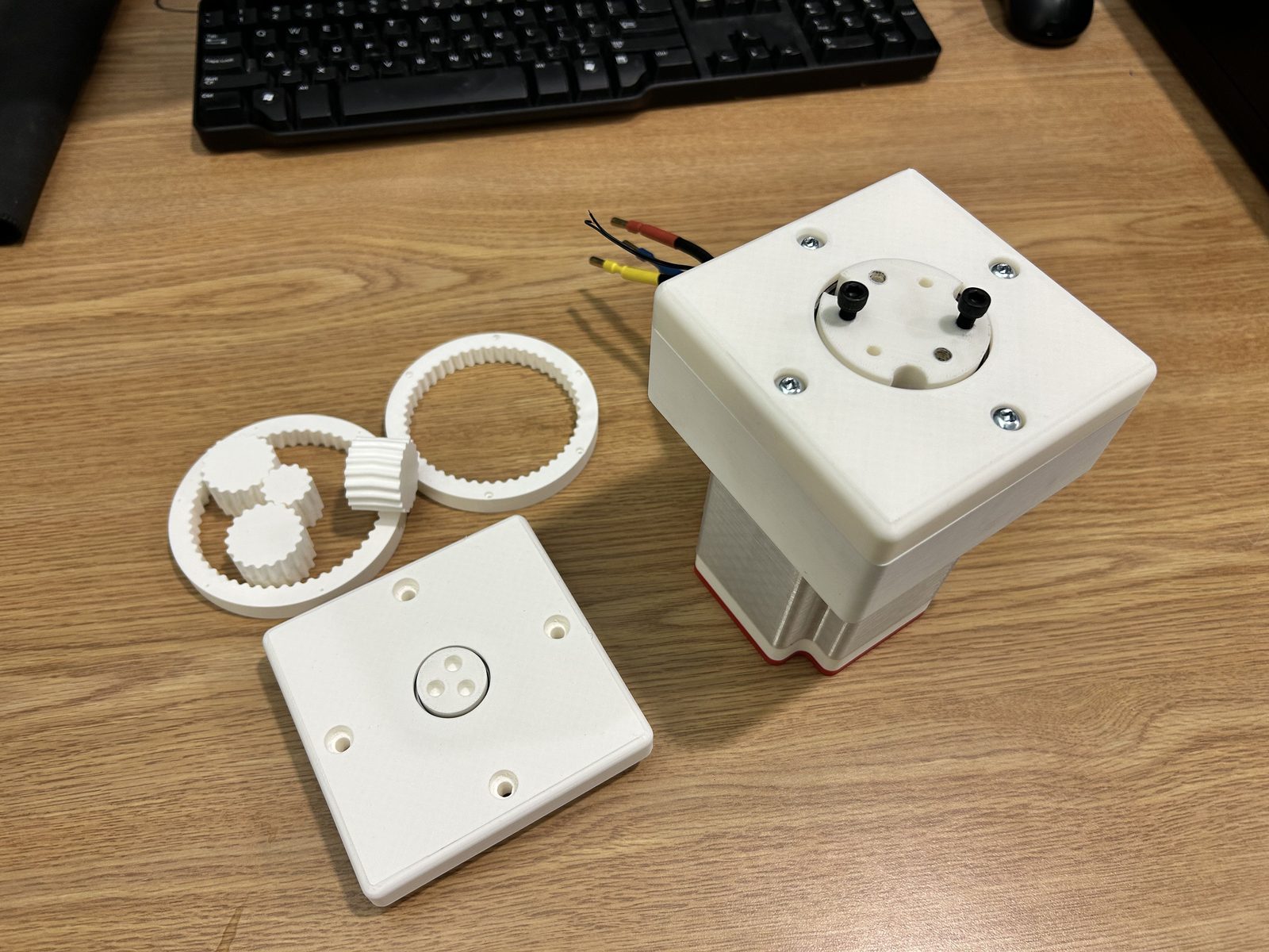 Printed carrier, ring gear and lid laid out beside the assembled gearbox on its motor